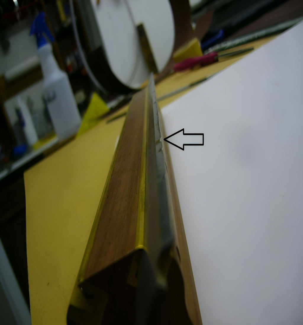 Close-up of a yellow object with a white surface, possibly a book or paper, in a workshop setting.